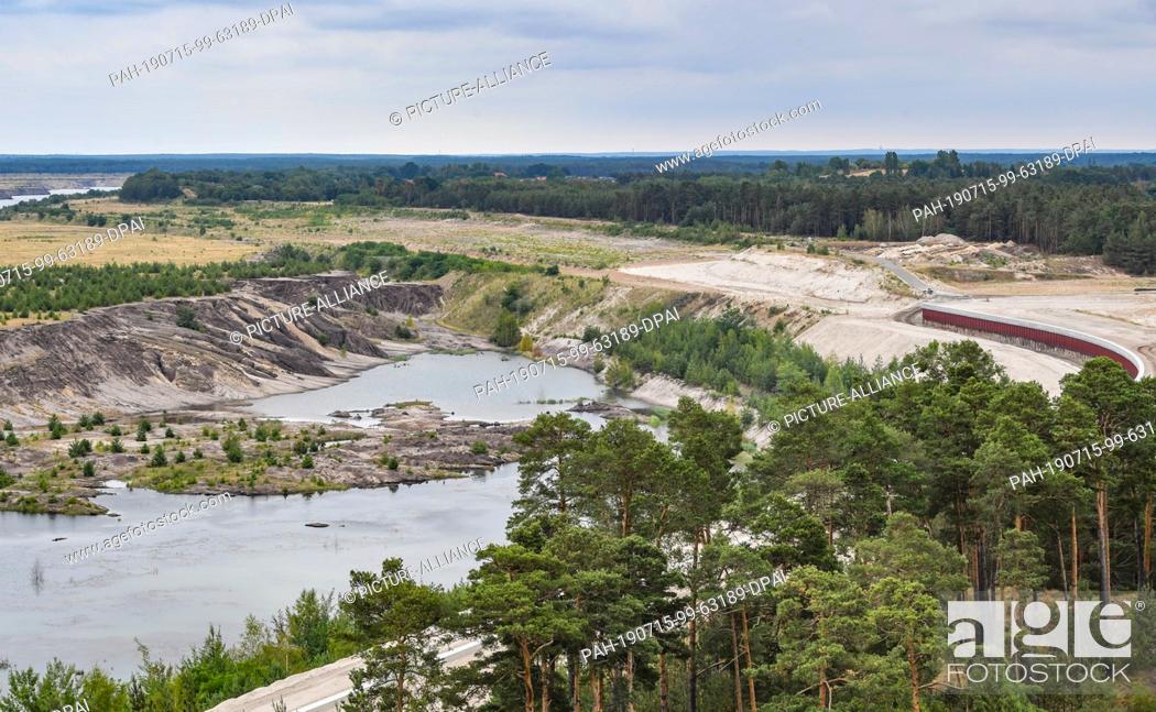 Stock Photo: 15 July 2019, Brandenburg, Cottbus: The future quay wall (r), on the edge of the former Cottbus-Nord opencast lignite mine, is currently under construction.