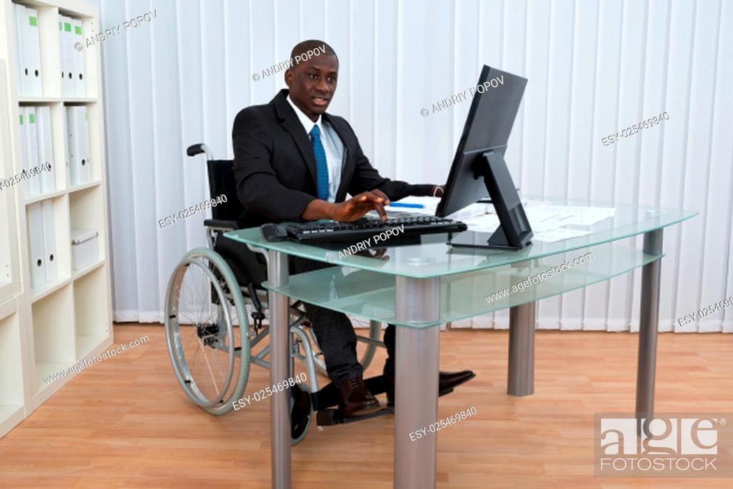 Stock Photo: Portrait Of Happy African Businessman Working In Office Sitting On Wheelchair.