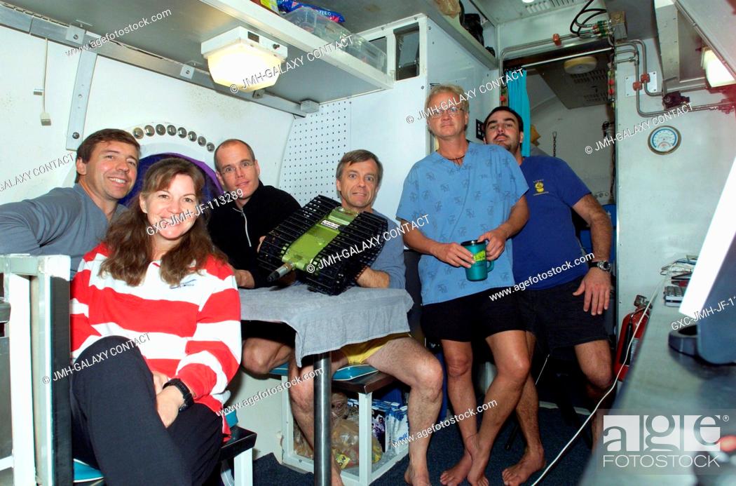 Stock Photo: The NEEMO-7 crew and habitat technicians Billy Cooksey and James Talacek (right) pose for a group photo along with a remotely operated rover at the galley table.