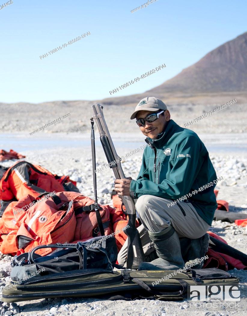 Stock Photo: 15 August 2019, Canada, Pond Inlet: The park ranger, Brian Koonoo, prepares his weapon at the beginning of a hike to the glacier at Pond Inlet.