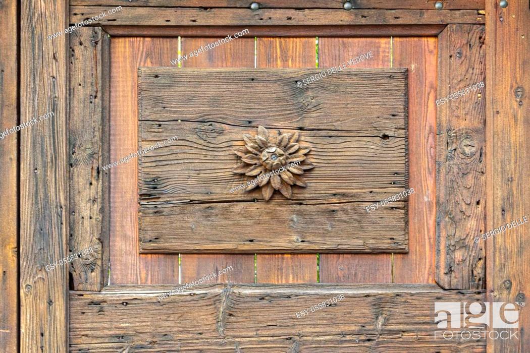 Photo de stock: a small flower carved on an old wooden door.