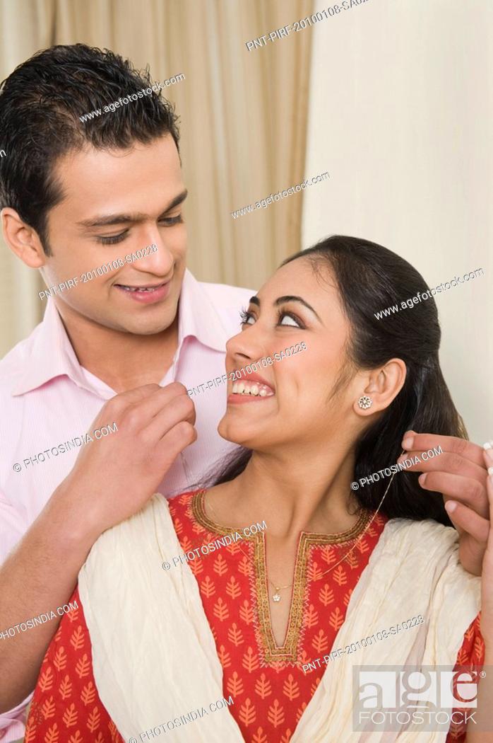 Stock Photo: Man putting a necklace on a woman's neck.