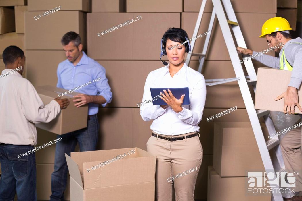 Imagen: Pretty warehouse manager using tablet during busy period in a large warehouse.