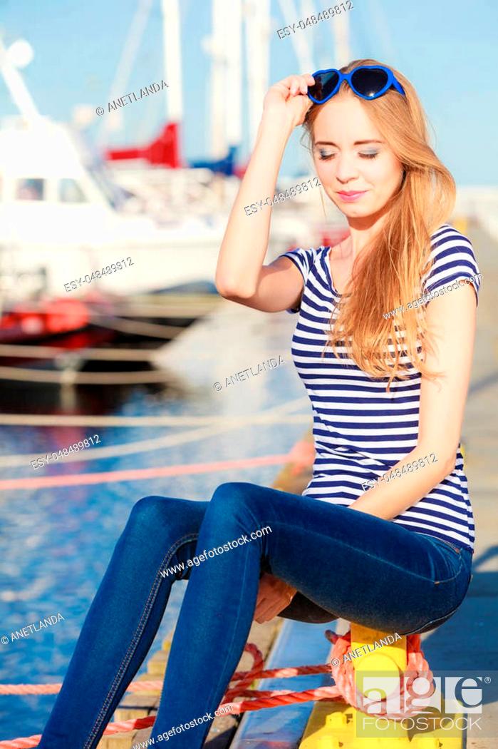 Stock Photo: Travel tourism and people concept. Fashion blonde girl with blue heart shaped sunglasses in marina against yachts in port.