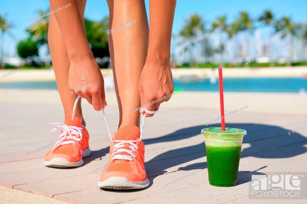 Stock Photo: Running woman runner with green vegetable smoothie. Fitness and healthy lifestyle concept with female model tying running shoe laces.