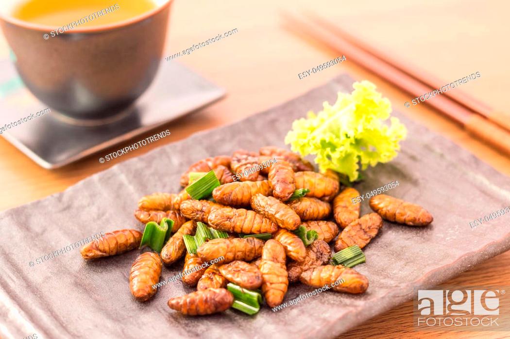 Stock Photo: Fried insects - Wood worm insect crispy with pandan after fried and add a light coating of sauce and garnish Thai pepper powder with chopsticks, tea.