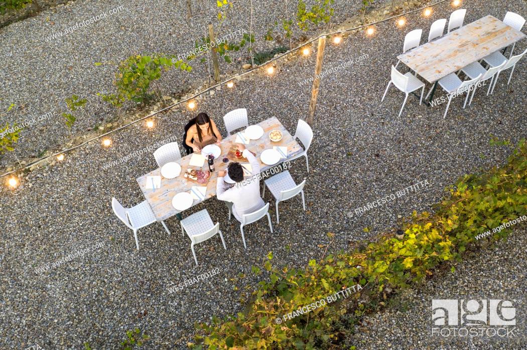 Stock Photo: Italy, Tuscany, Siena, top view of young couple having dinner in a vineyard.