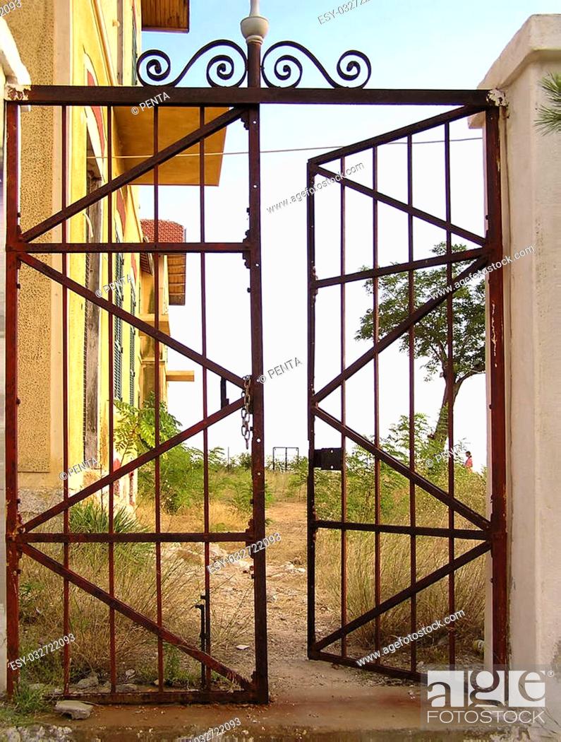 Imagen: Old rusted metal gate at abandoned estate, partly opened.