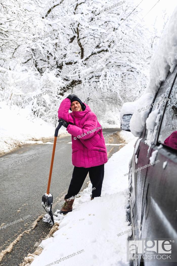 Stock Photo: Man with snow shovel standing on road in winter season.