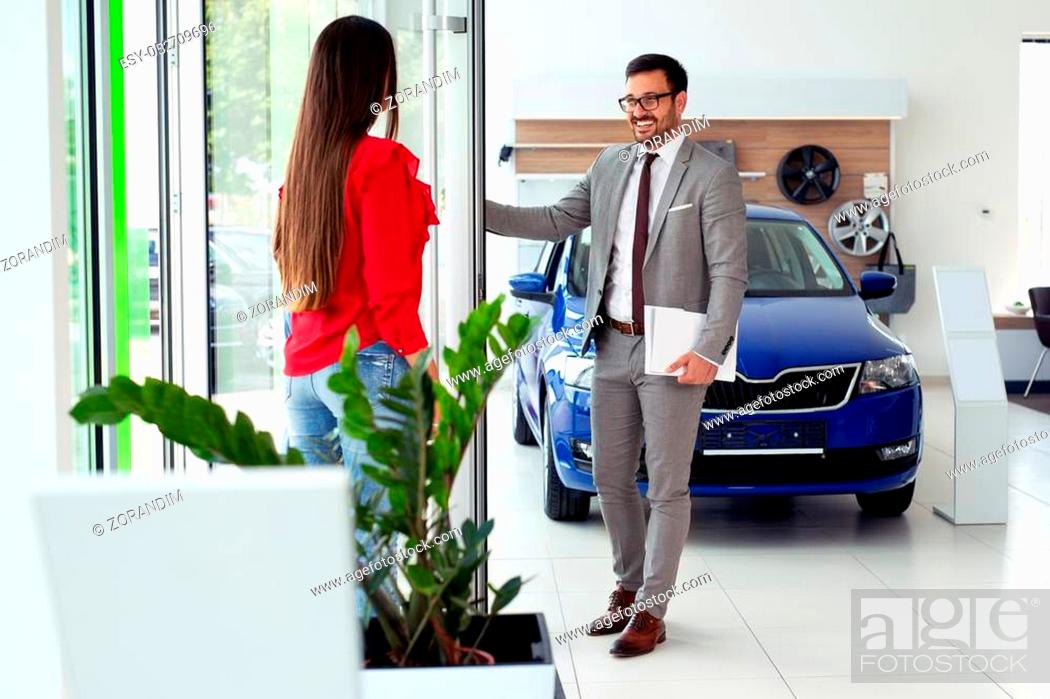 Stock Photo: Happy girl enjoys buying a new car in the showroom.