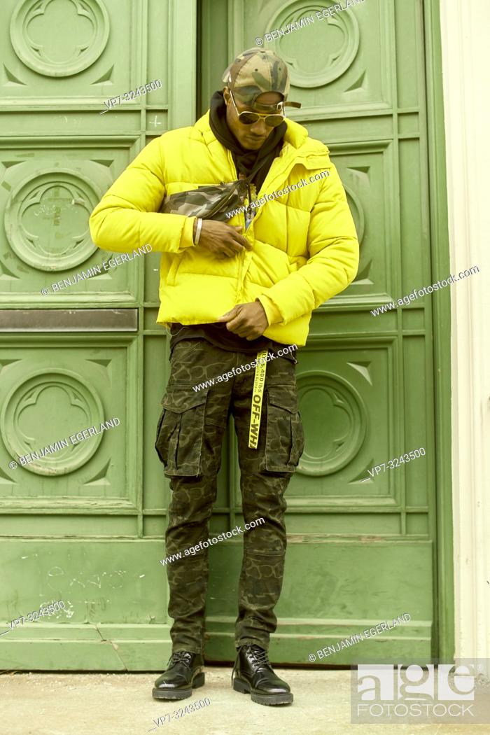 Stock Photo: stylish man wearing trendy street style men's outfit clothing, yellow jacket, standing in front of opening green door, in city Munich, Germany.