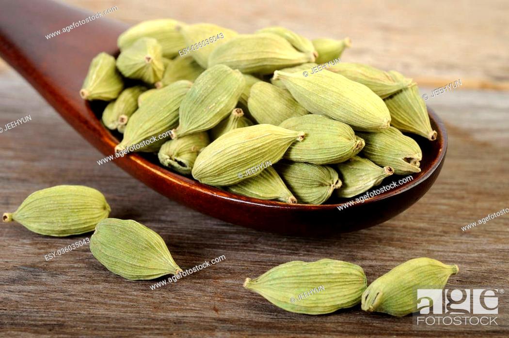 Stock Photo: green cardamom pods in wooden spoon.