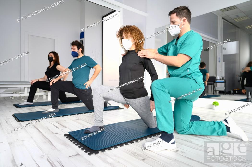 Stock Photo: Group of persons on yoga mats assisted by physiotherapist at the rehabilitation clinic. High quality photo.
