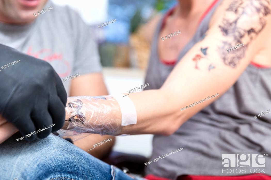 Stock Photo: Close-up of the wrapped forearm of a young woman after getting a new cool tattoo in a modern studio with sterile safety supplies.