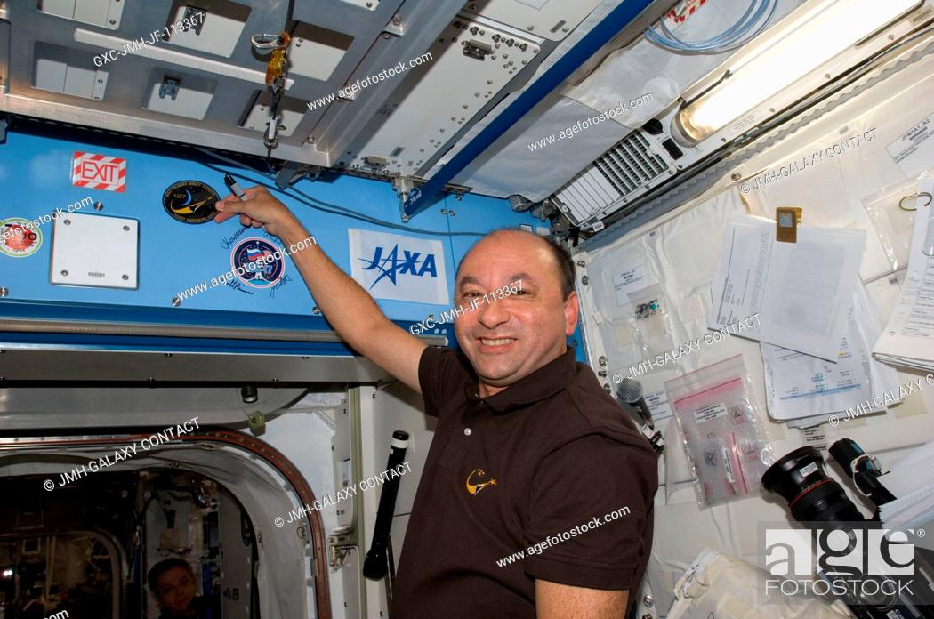 Stock Photo: Astronaut Mark Polansky, STS-127 commander, places the STS-127 patch above a hatch in the Kibo laboratory, which adds to the growing collection of insignias.
