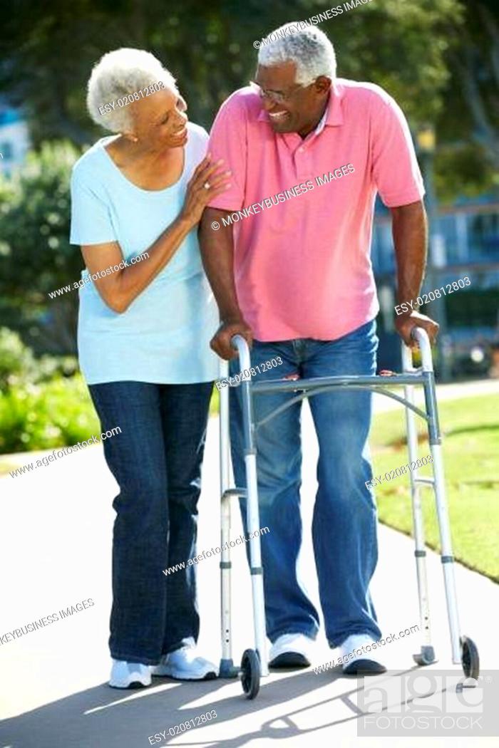 Stock Photo: Senior Woman Helping Husband With Walking Frame.