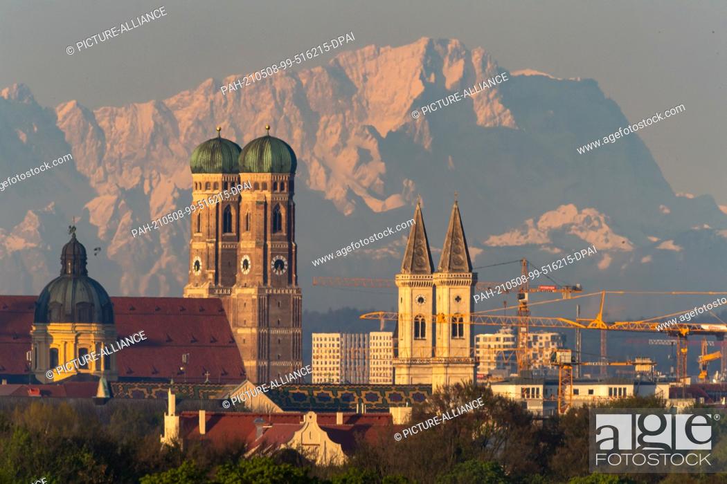 Stock Photo: 08 May 2021, Bavaria, Munich: The Theatinerkirche (l-r), the Frauenkirche and the Sankt Ludwig-Kirch of the Bavarian capital can be seen in the early morning.