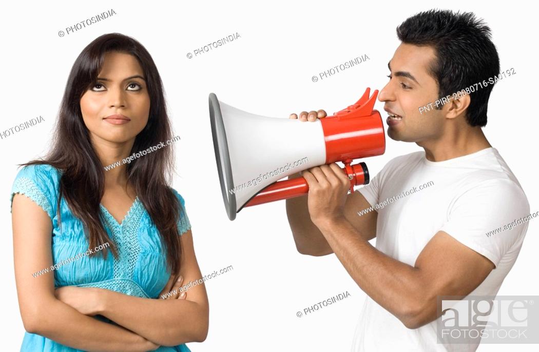 Stock Photo: Side profile of a young man blowing a bullhorn with a teenage girl standing beside him.