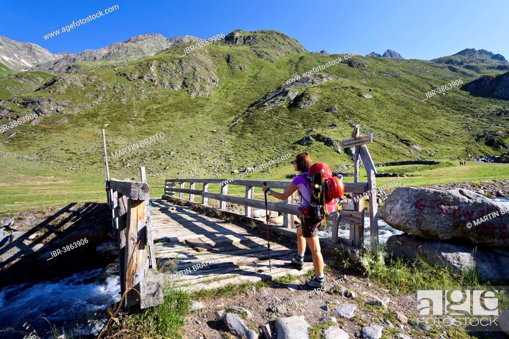 Stock Photo: Female mountain climber at Timmelsalm alpine pasture crossing Timmlserbach stream, during the ascent to Müller Hut through the Passeiertal valley along the.