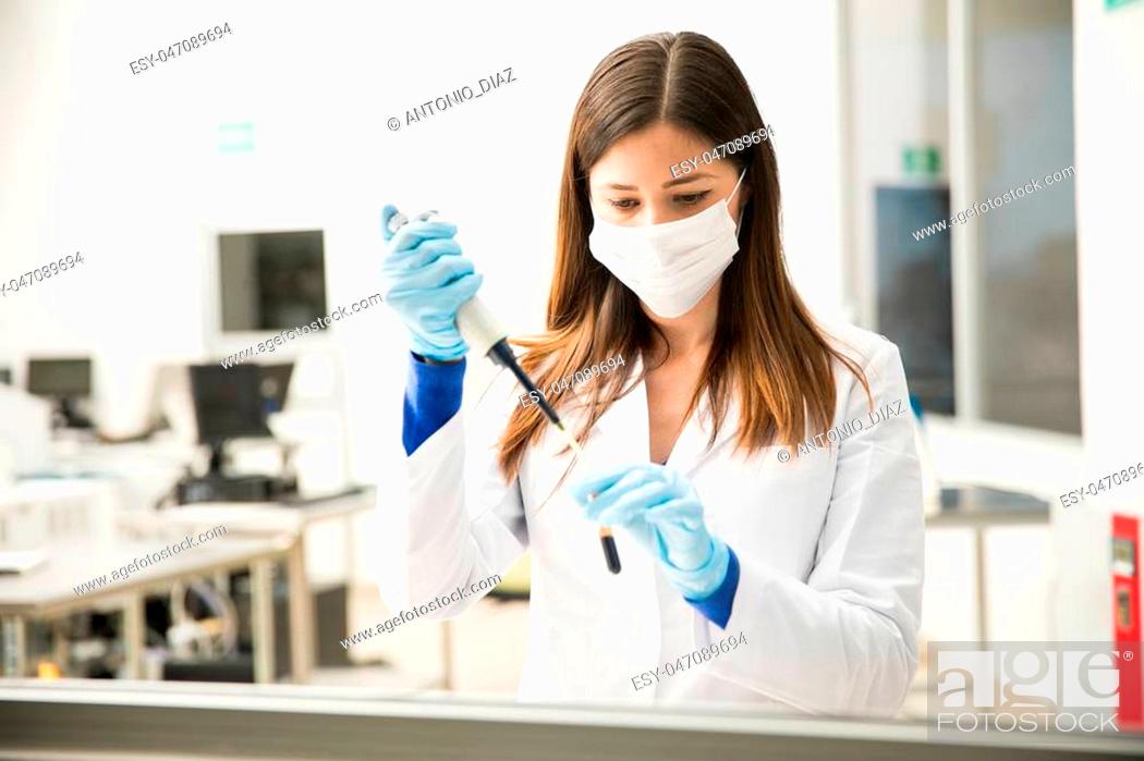 Stock Photo: Pretty female chemist using a pipette to prepare a blood sample for testing in a lab.