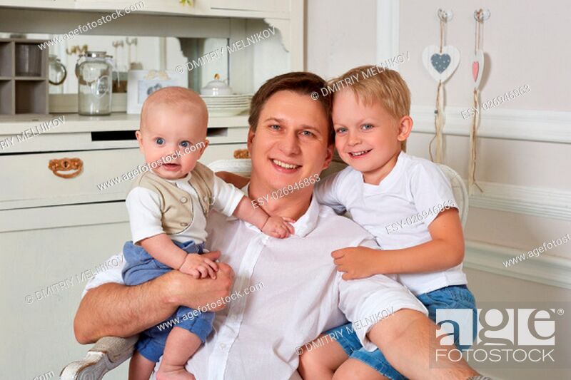 Stock Photo: Happy father with two small sons are sitting in an armchair in the room.
