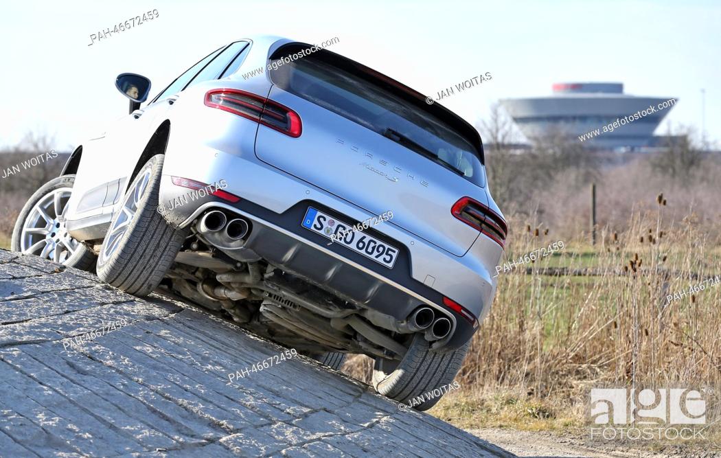 Stock Photo: A new Porsche Macan drives along the offroad test track in front of the diamond-shaped customer center of the Porsche factory in Leipzig, Germany.