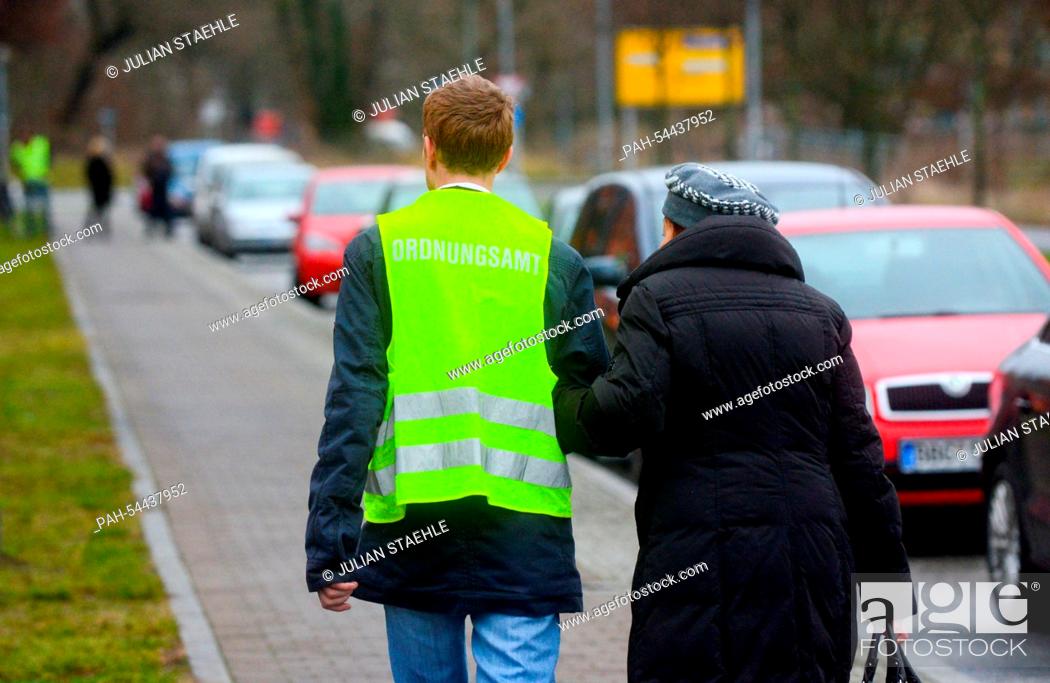 Stock Photo: An Office of Public Order employee helps a senior citizen escape the blocked circuit in Potsdam, Germany, 18 December 2014.