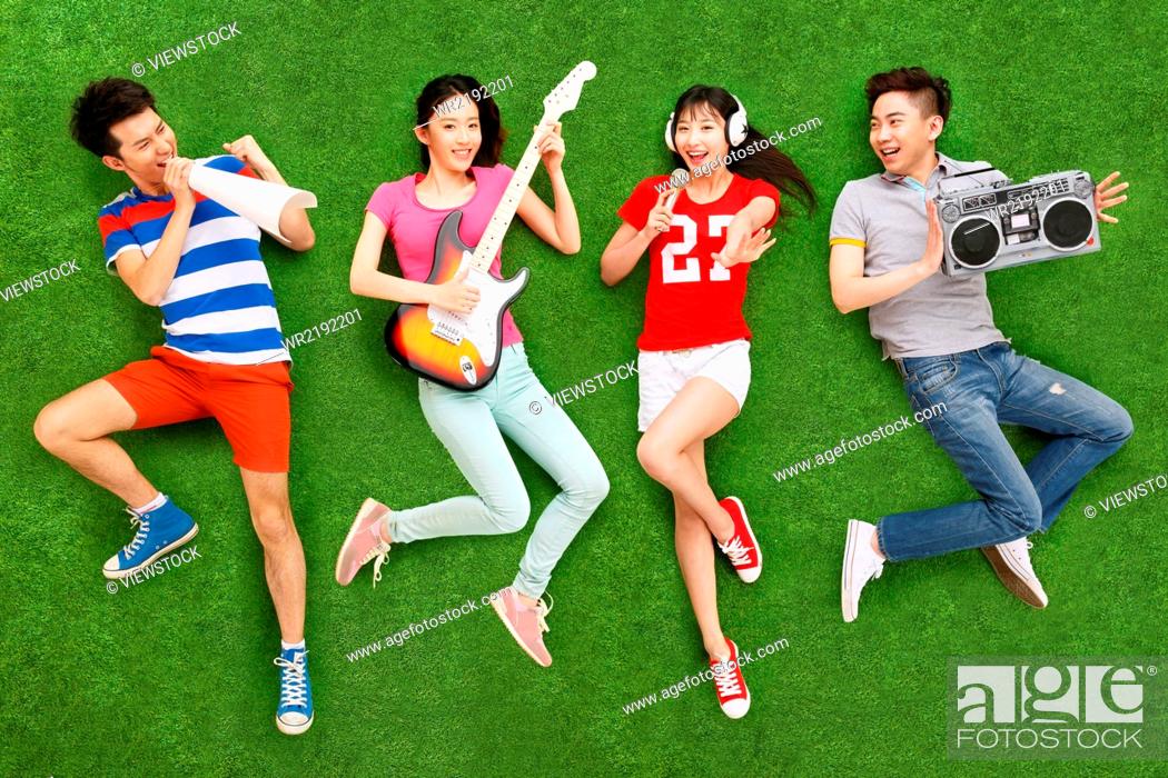 Stock Photo: Young people on grass playing guitar and singing.