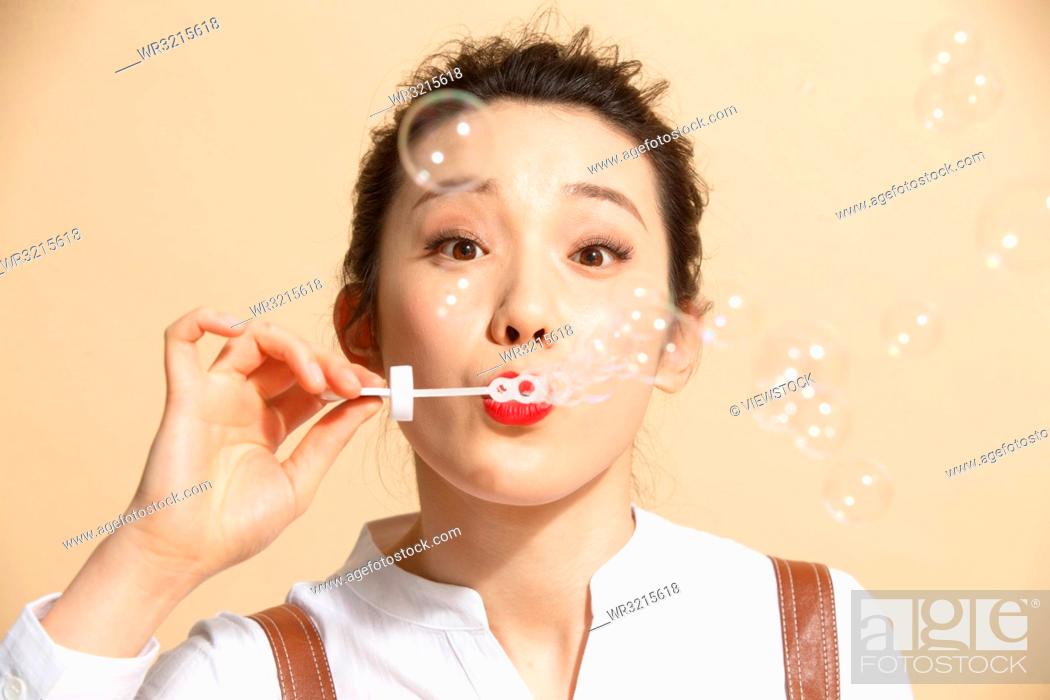 Stock Photo: Young woman blowing bubbles.