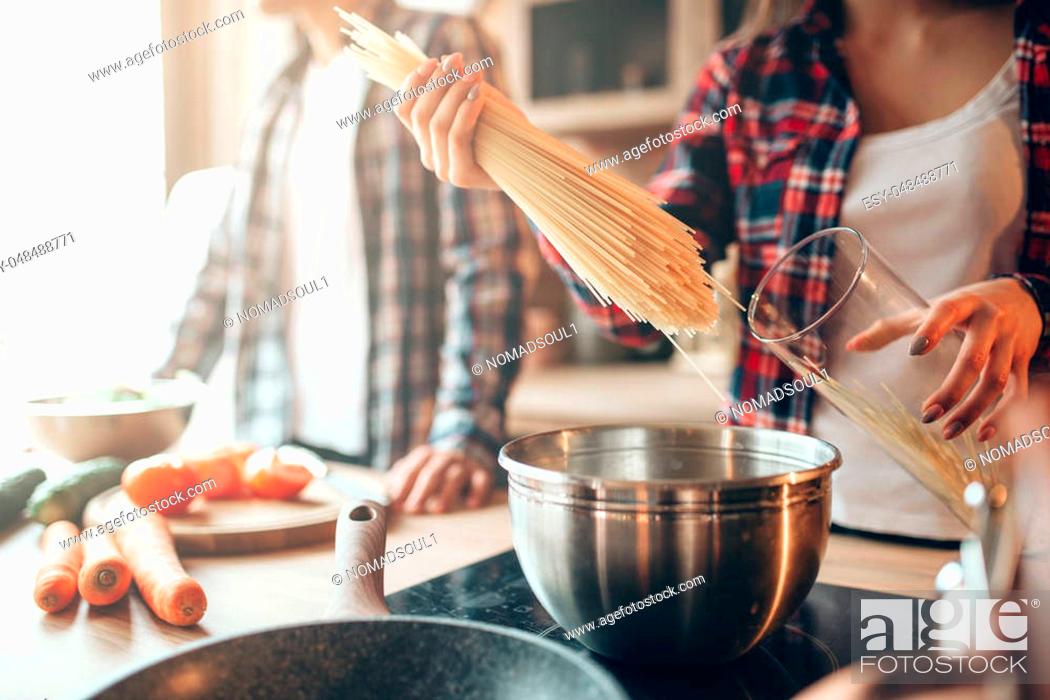 Stock Photo: Couple cooking fresh vegetable salad and spaghetti on the kitchen. Diet food preparation. Couple prepares romantic dinner, healthy lifestyle.