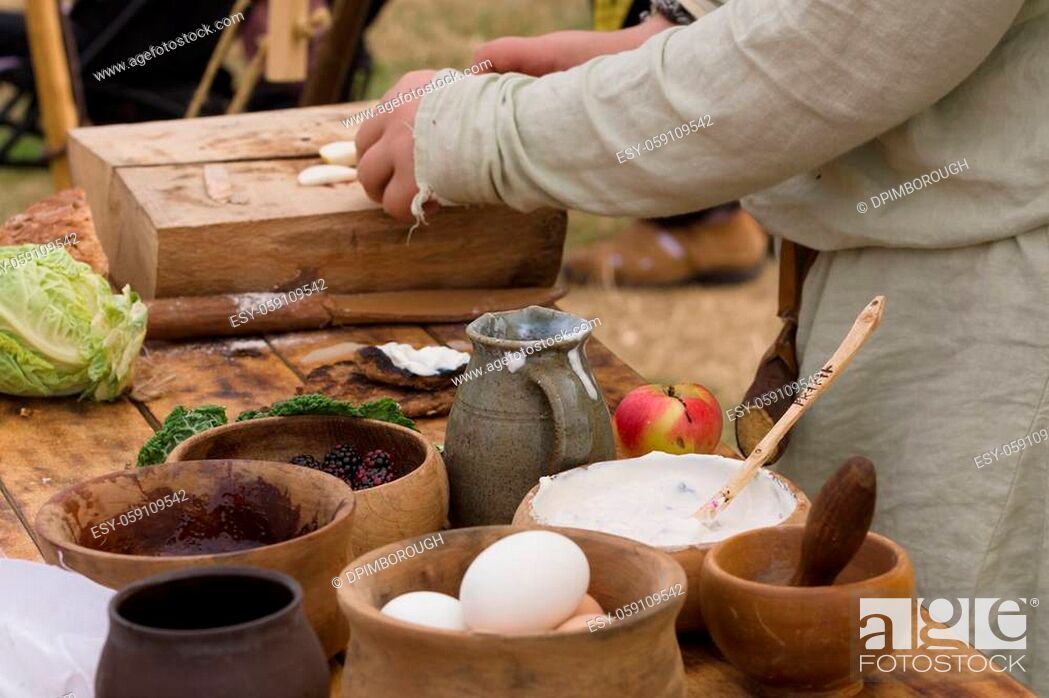 Stock Photo: Medieval food preparation including bread, butter, cheese, fruit in wooden bowls or trenchers.