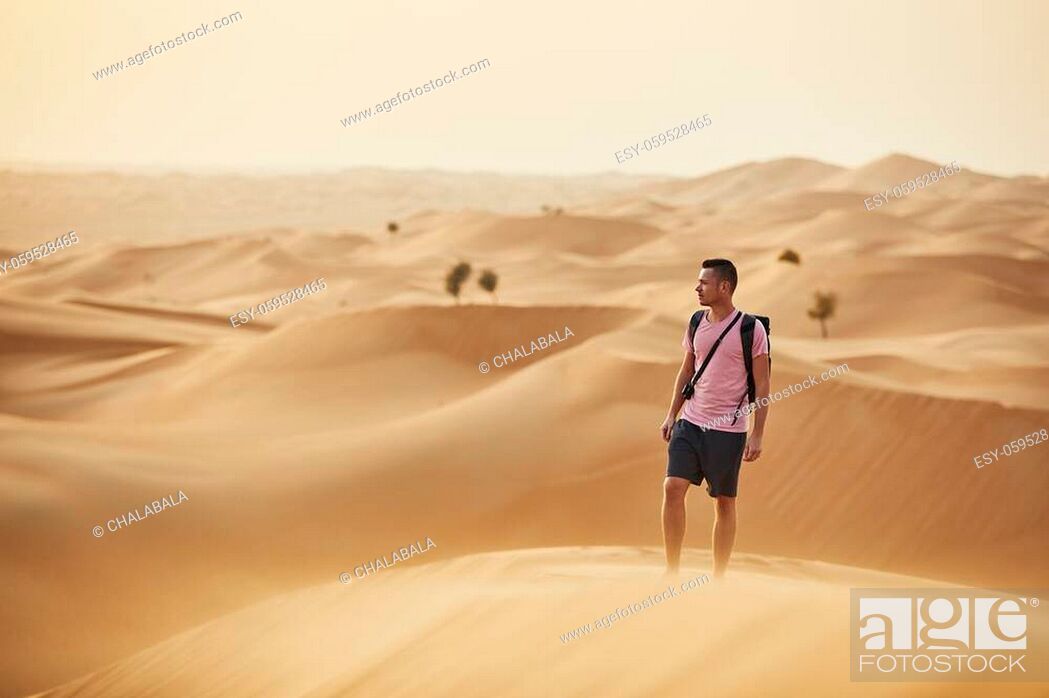 Stock Photo: Desert adventure. Man standing on sand dune. Abu Dhabi, United Arab Emirates.