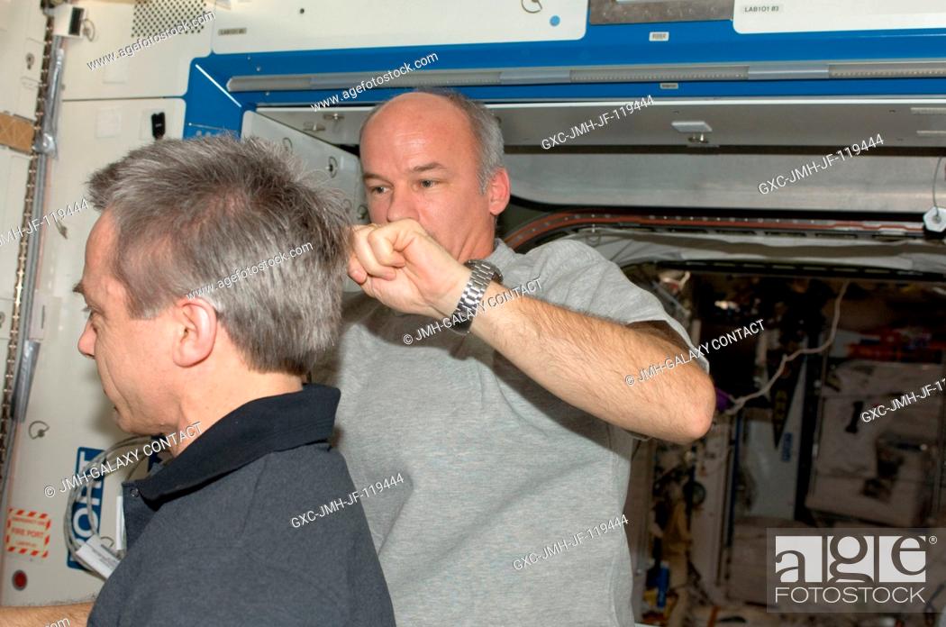 Stock Photo: NASA astronaut Jeffrey Williams, Expedition 21 flight engineer, trims Canadian Space Agency astronaut Robert Thirsk's hair in the Destiny laboratory of the.