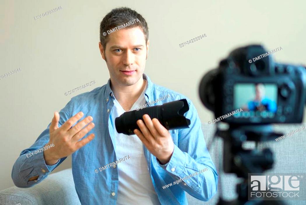 Stock Photo: Handsome man making video blog about photo camera lenses.