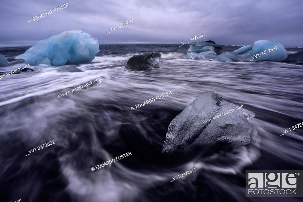 Stock Photo: Broken ice from washed up Icebergs on Jokulsarlon black beach at sunset Jokulsarlon South east Iceland.