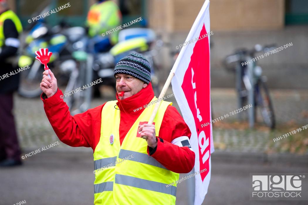 Stock Photo: 18 November 2019, Baden-Wuerttemberg, Stuttgart: A man with a ver.di flag runs the demonstration through downtown Stuttgart. On 18.11.