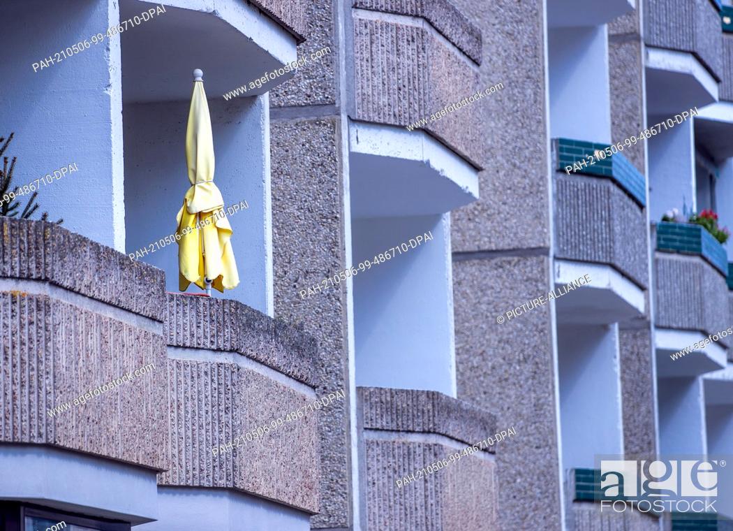 Stock Photo: 28 April 2021, Mecklenburg-Western Pomerania, Pasewalk: A yellow parasol stands on a balcony in a prefabricated apartment block.