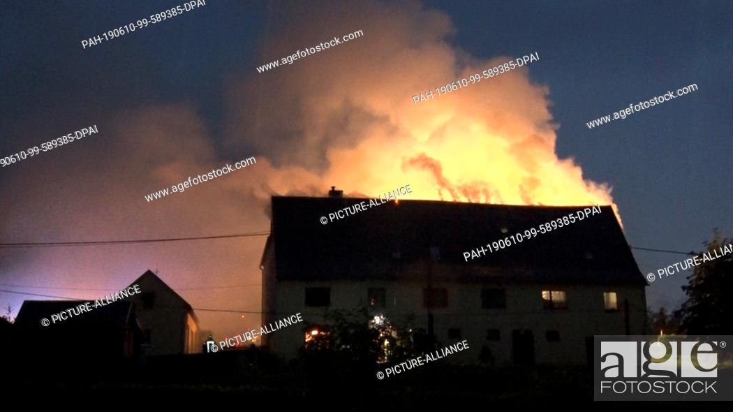 Stock Photo: 10 June 2019, Germany (German), Steinbach: The roof of a house burns after a lightning strike. A violent thunderstorm had brought heavy rainfalls and hail as.