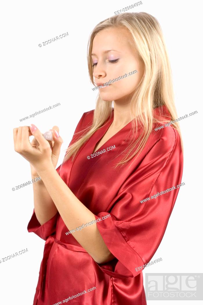 Stock Photo: young woman dressed red bathrobe painting nails (pure white background).