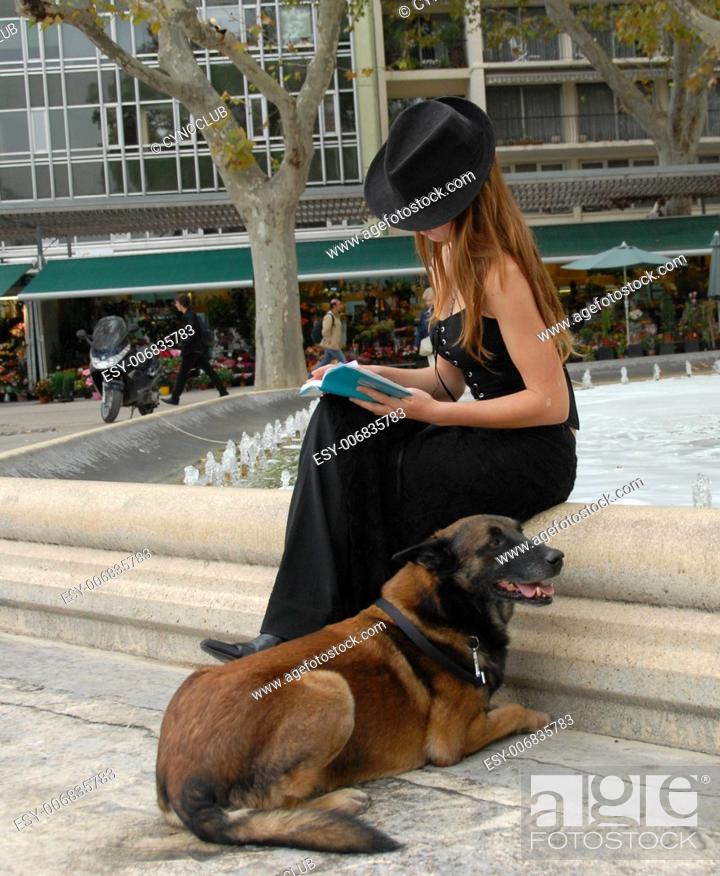 Stock Photo: beautiful teenager reading her book with her dog.