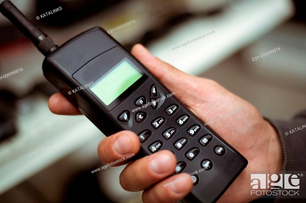Stock Photo: Male hand holds a black plastic vintage cell or radio telephone receiver.