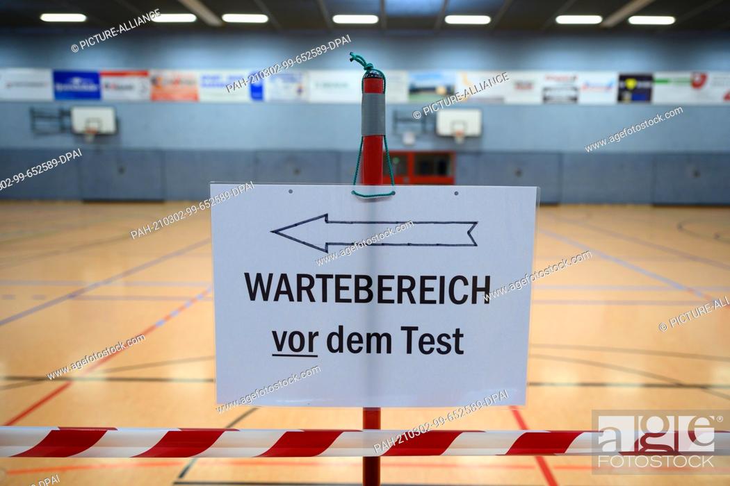 Stock Photo: 02 March 2021, Saxony, Radeberg: A sign with the inscription ""Waiting area before the test"" stands in the sports hall as part of a mass test for residents of.