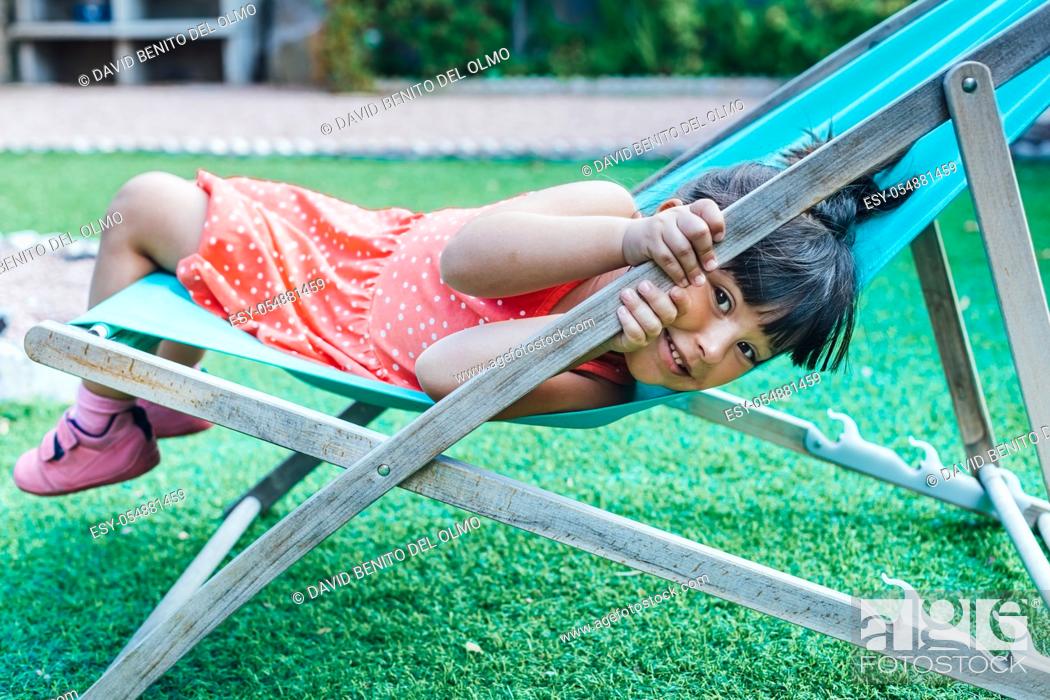 Imagen: A black-haired girl lying on a lounger in the garden in summer.