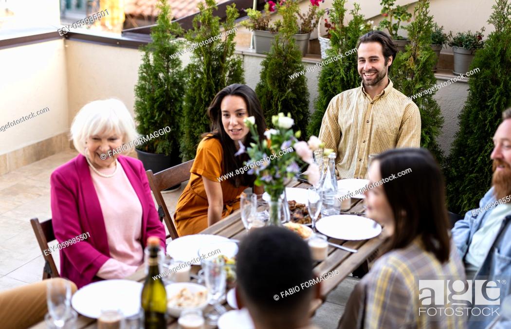 Photo de stock: Storytelling footage of a multiethnic group of people dining on a rooftop. Family and friends make a reunion at home.