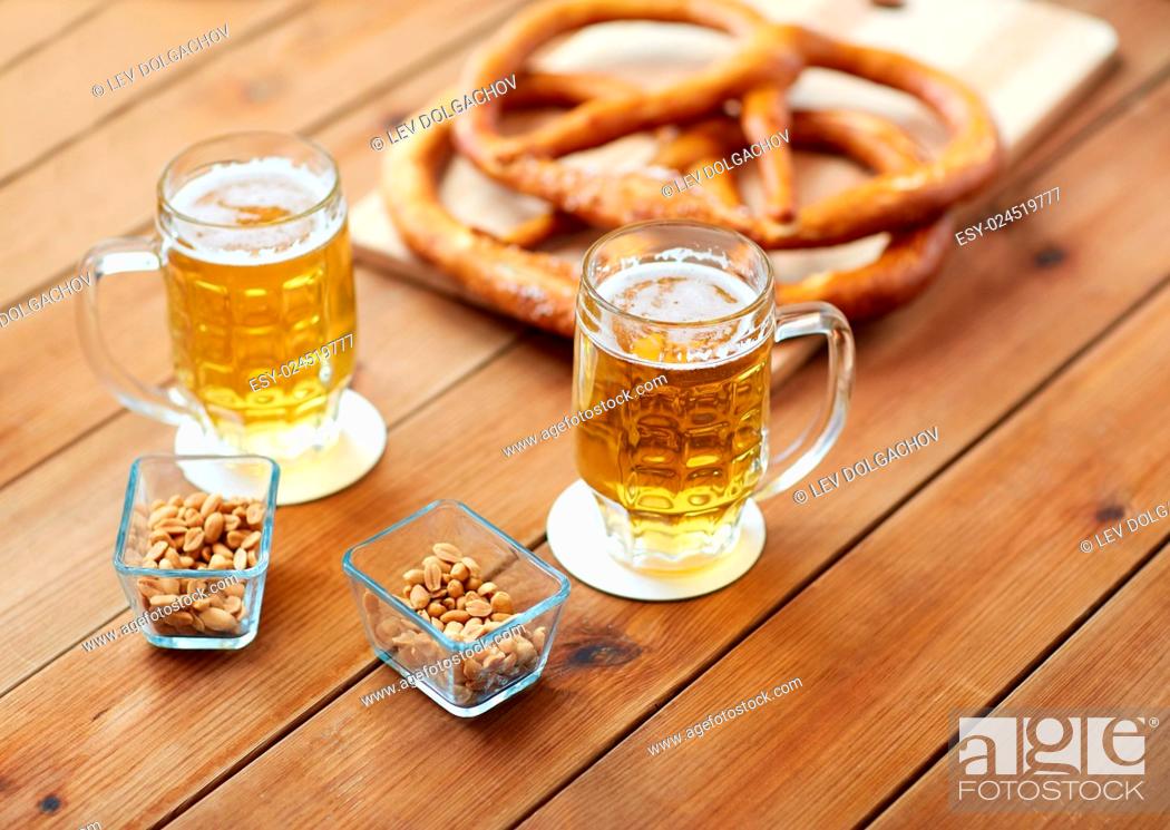 Stock Photo: food, baking, cooking and pastry concept - close up of beer in glass, pretzels and peanuts on wooden table at pub.