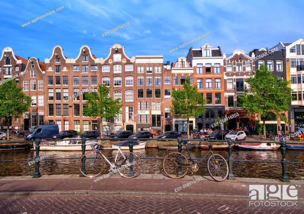 Stock Photo: Typical buildings, canal and bikes in Amsterdam by day, Netherlands.