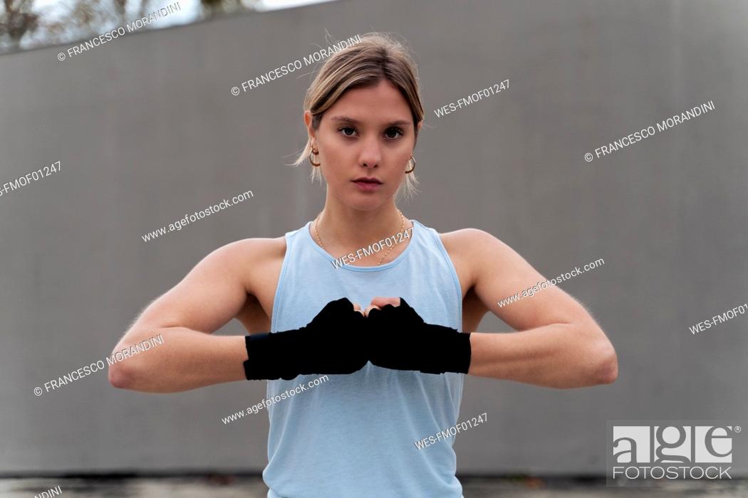 Stock Photo: Sportswoman with bandage wrapped hand standing against wall.