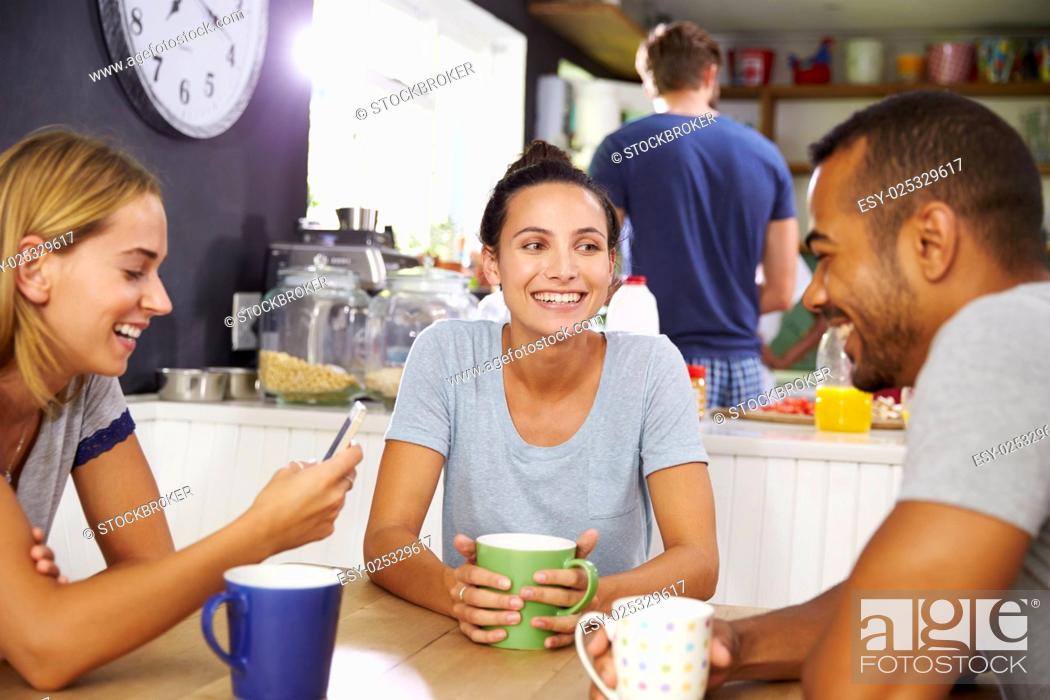 Stock Photo: Group Of Friends Enjoying Breakfast In Kitchen Together.