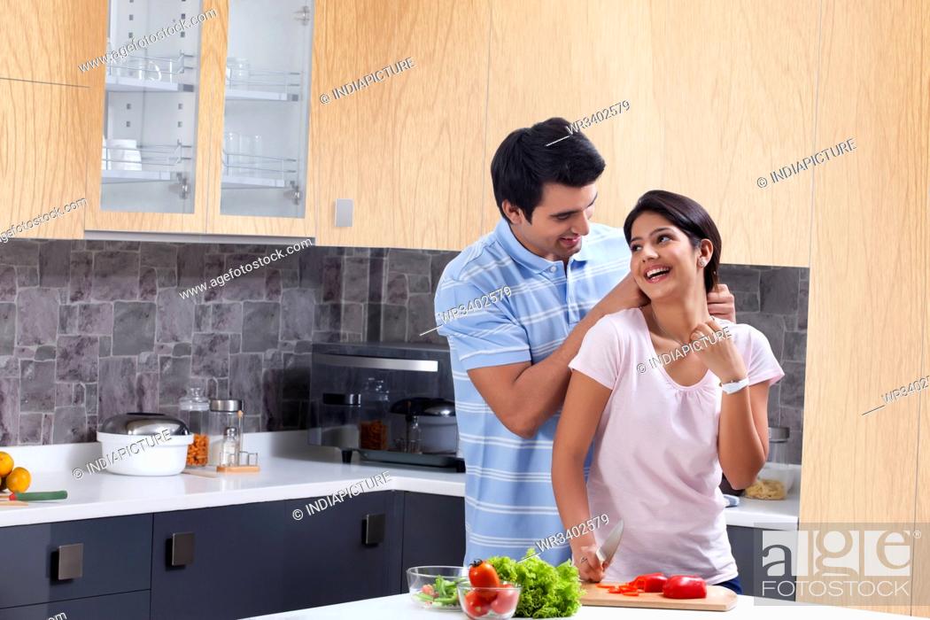 Stock Photo: Loving man putting necklace on woman in kitchen.