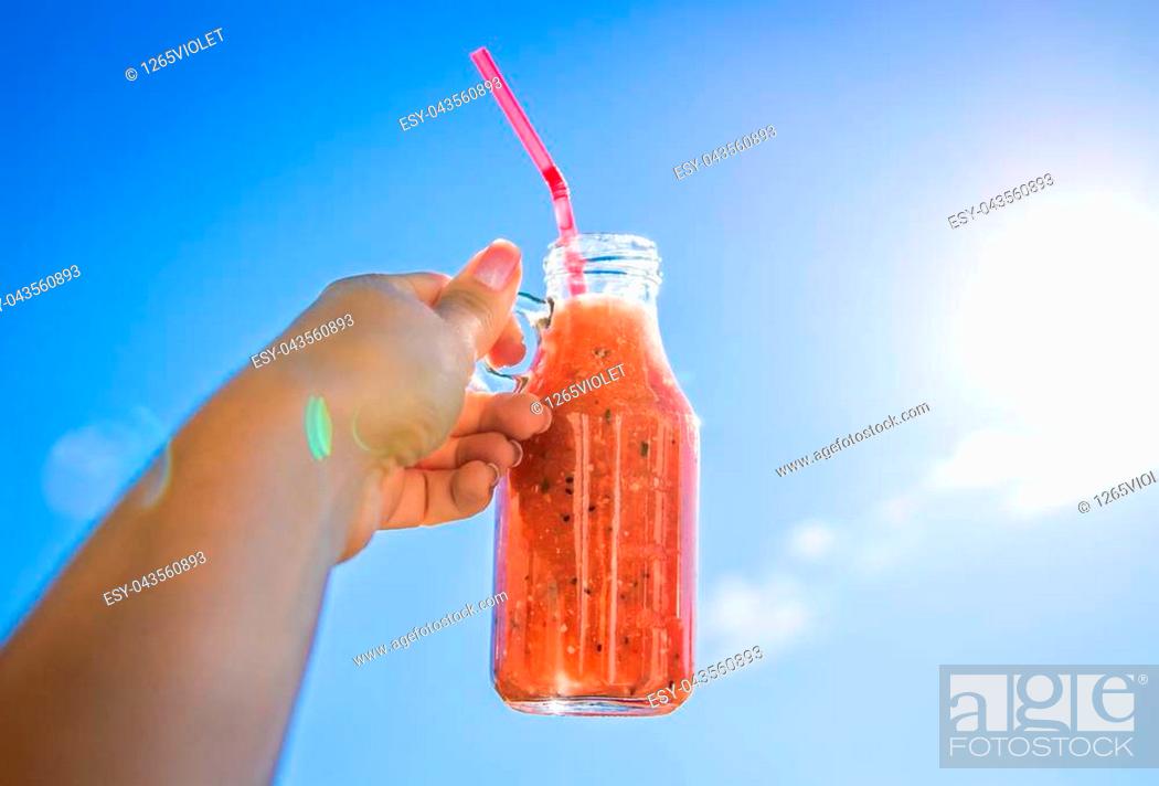 Stock Photo: Woman holds a bottle of smoothie against the blue sky. Healthy breakfast. New day with beginning. Dieting.